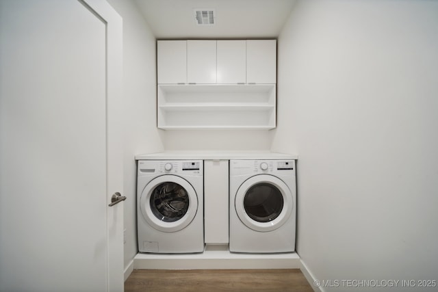 laundry area with washing machine and clothes dryer and light hardwood / wood-style floors