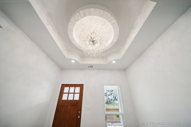 entrance foyer featuring a raised ceiling and a chandelier