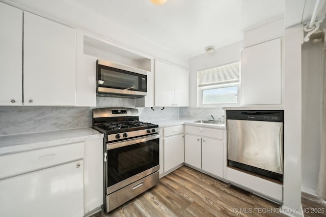 kitchen with white cabinets, sink, wood-type flooring, and stainless steel appliances