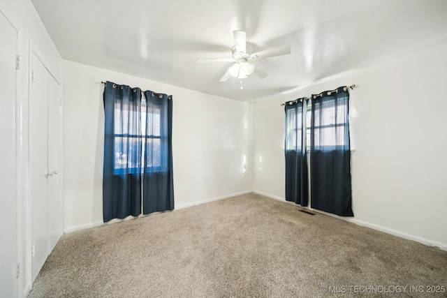 unfurnished room with ceiling fan, carpet floors, and a wealth of natural light