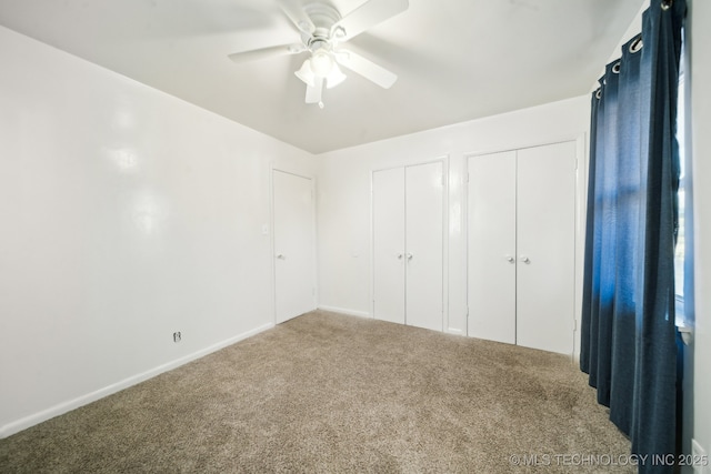 unfurnished bedroom with ceiling fan, carpet, and two closets