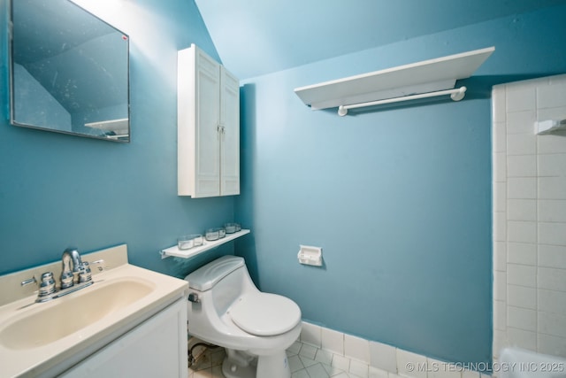 bathroom featuring tile patterned flooring, vanity, toilet, and vaulted ceiling