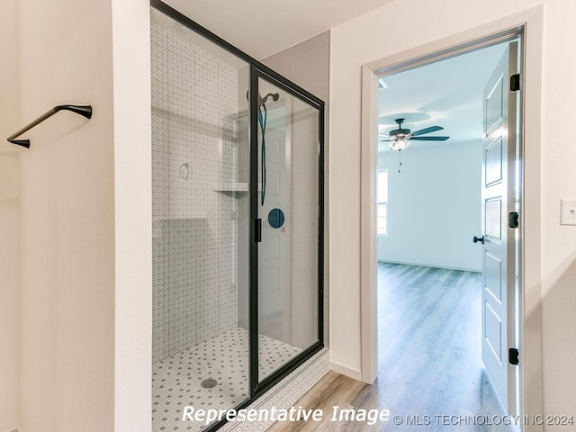 bathroom with a shower with shower door, ceiling fan, and hardwood / wood-style flooring