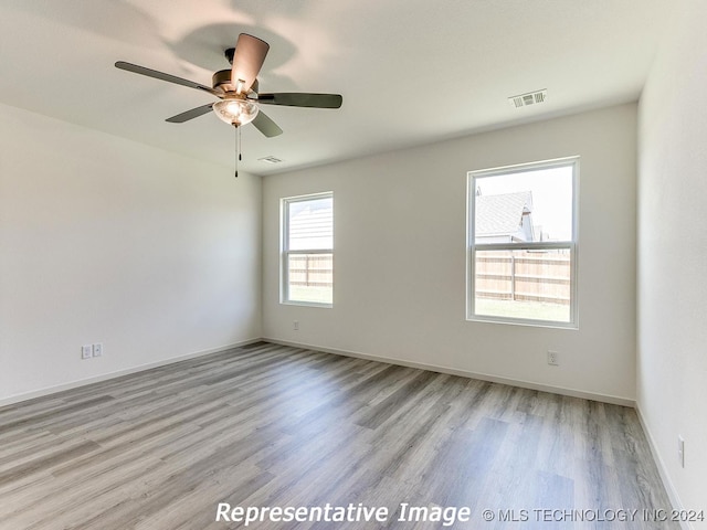 spare room featuring ceiling fan, light hardwood / wood-style floors, and a healthy amount of sunlight