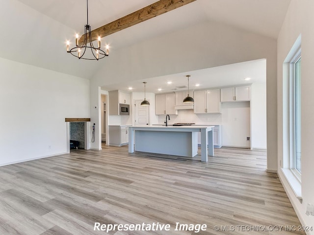 kitchen with hanging light fixtures, light hardwood / wood-style flooring, a chandelier, beamed ceiling, and a kitchen island with sink