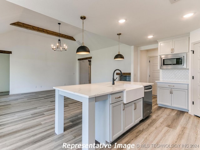 kitchen featuring light wood-type flooring, stainless steel appliances, an island with sink, and vaulted ceiling with beams