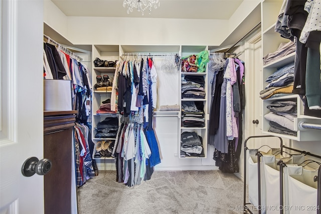 walk in closet featuring light carpet and a notable chandelier