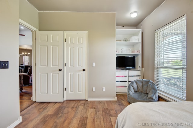 bedroom with multiple windows, an inviting chandelier, and hardwood / wood-style flooring