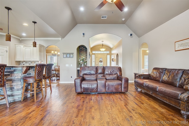 living room featuring hardwood / wood-style flooring, ceiling fan with notable chandelier, and vaulted ceiling