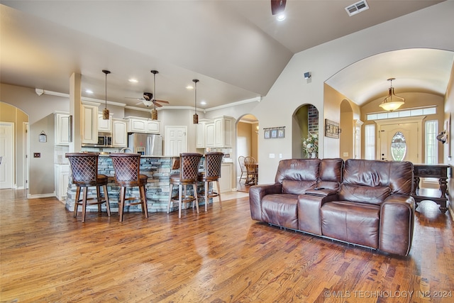 living room featuring ceiling fan, light hardwood / wood-style floors, crown molding, and vaulted ceiling