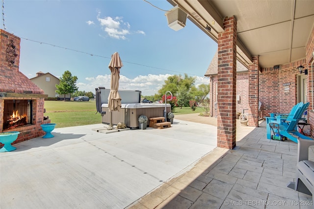 view of patio / terrace featuring a hot tub and an outdoor brick fireplace