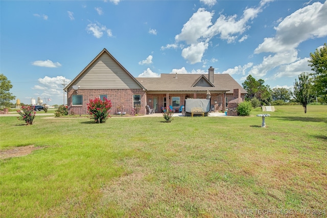 back of house with a lawn and a patio