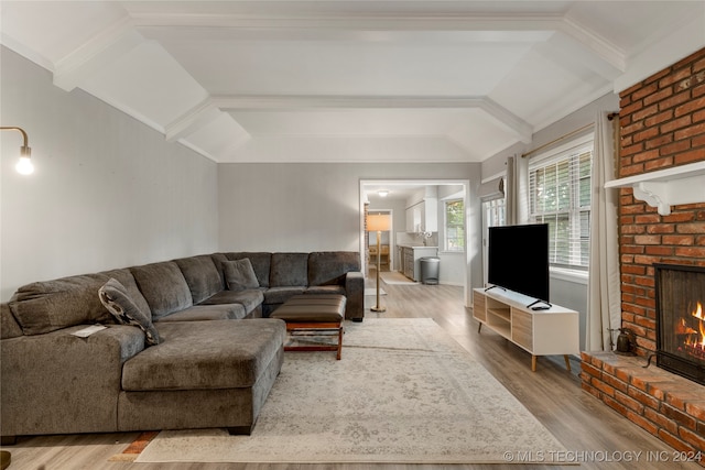 living room featuring vaulted ceiling with beams, ornamental molding, a fireplace, and hardwood / wood-style floors