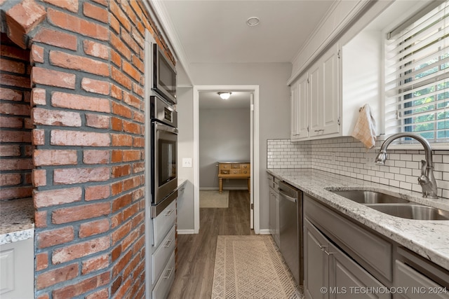 kitchen featuring appliances with stainless steel finishes, light stone countertops, light wood-type flooring, and sink