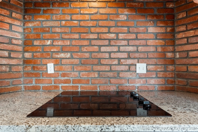 interior details featuring light stone countertops and black electric stovetop