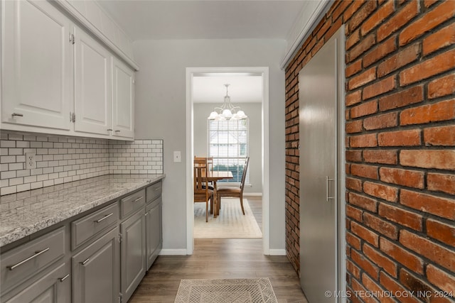 kitchen featuring light stone counters, pendant lighting, white cabinetry, a notable chandelier, and light wood-type flooring