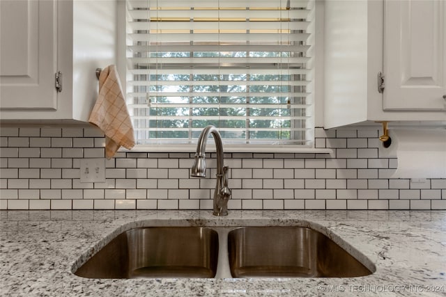 kitchen featuring backsplash, white cabinets, light stone counters, and sink