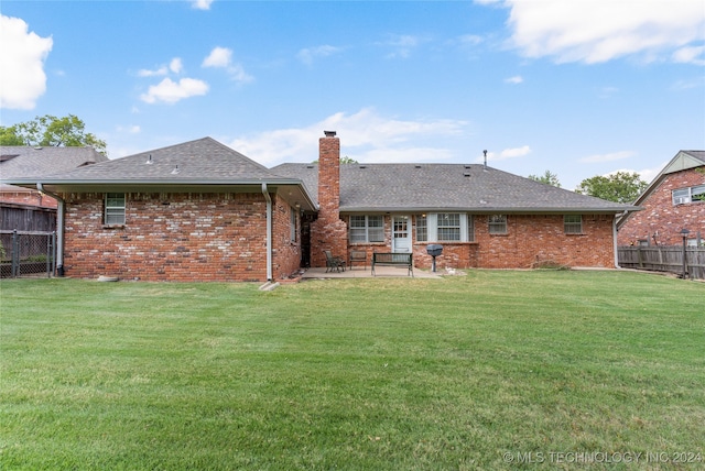 rear view of property with a patio and a lawn