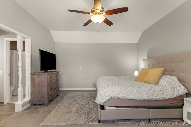 bedroom featuring ceiling fan, light colored carpet, lofted ceiling, and ensuite bathroom