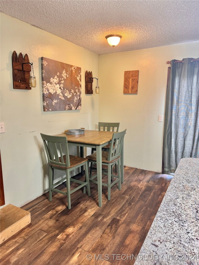 dining room featuring dark hardwood / wood-style floors and a textured ceiling