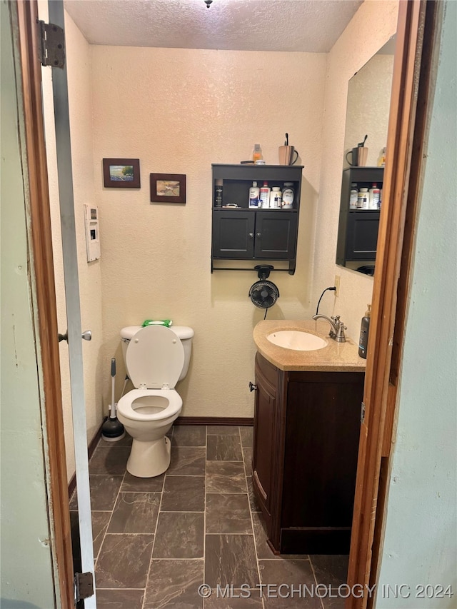 bathroom featuring vanity, toilet, and a textured ceiling