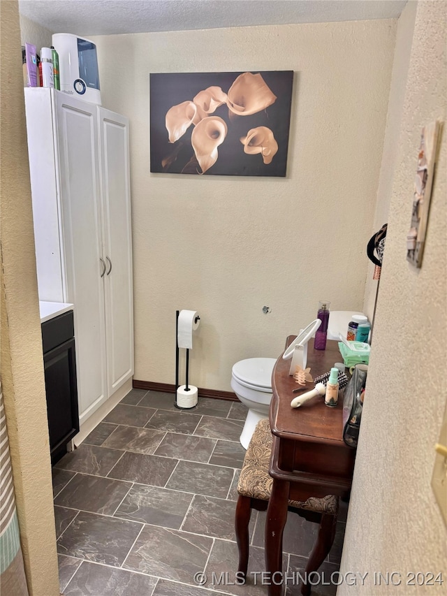 bathroom featuring vanity, toilet, and a textured ceiling