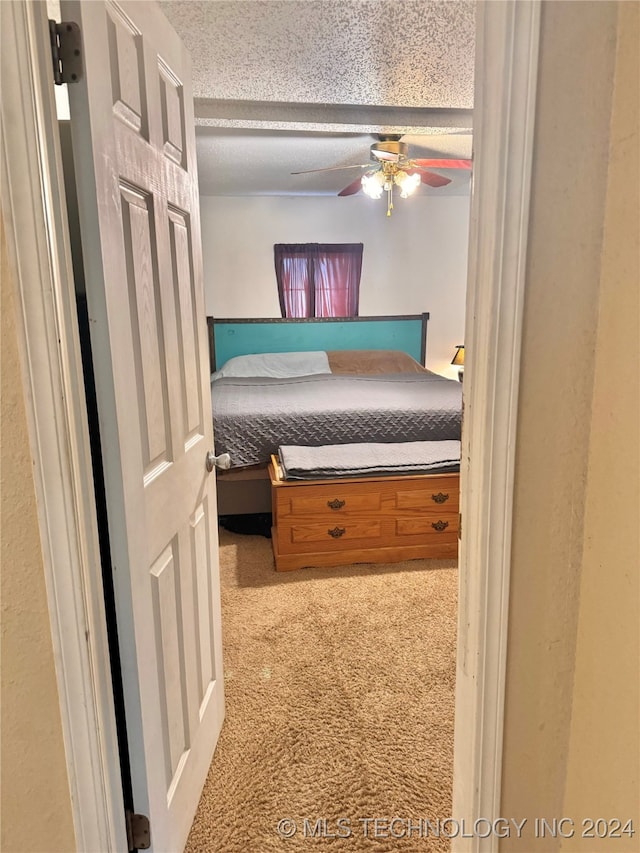 unfurnished bedroom featuring ceiling fan, light carpet, and a textured ceiling