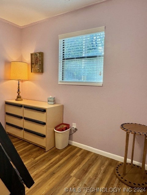 bedroom featuring baseboards, wood finished floors, and ornamental molding