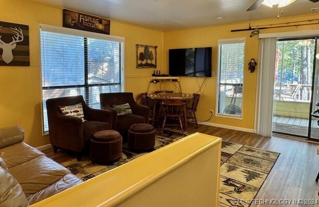 living area featuring baseboards, wood finished floors, and a ceiling fan