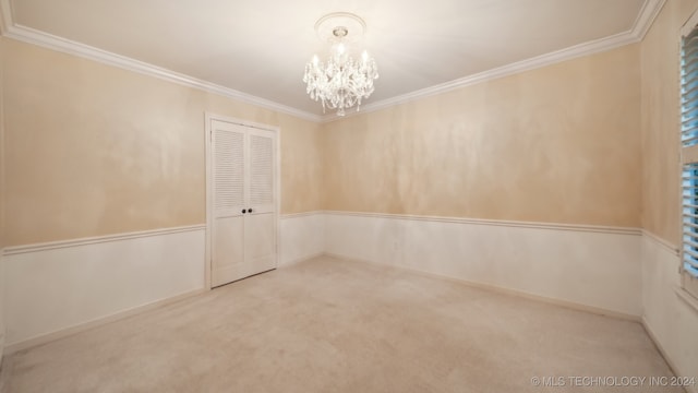 spare room featuring a chandelier, carpet flooring, and crown molding