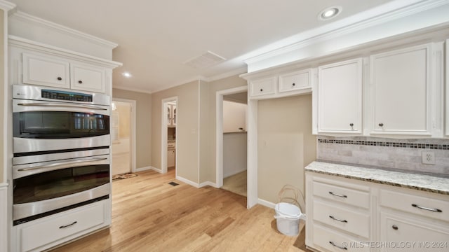 kitchen featuring decorative backsplash, white cabinetry, light wood-type flooring, and stainless steel double oven