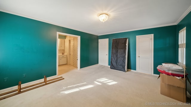 carpeted bedroom featuring ensuite bath and crown molding