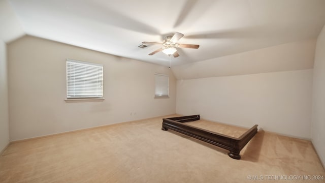 unfurnished bedroom with light carpet, ceiling fan, and vaulted ceiling