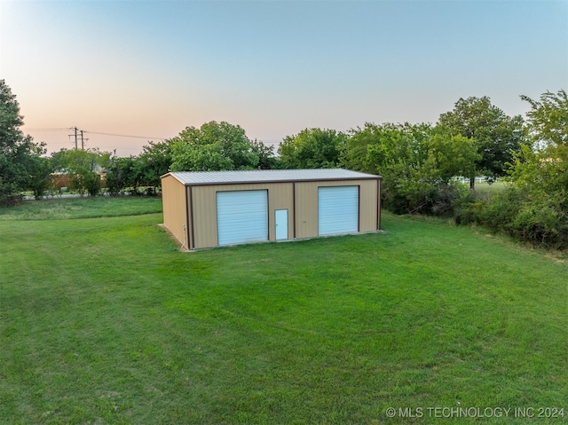 outdoor structure at dusk featuring a yard and a garage