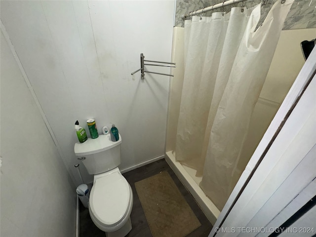 bathroom with a shower with shower curtain and toilet