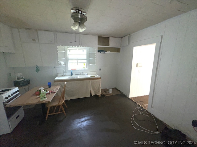 kitchen featuring white gas range oven, ceiling fan, white cabinetry, and sink