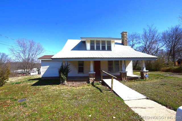 view of front of house featuring a chimney, a porch, and a front yard