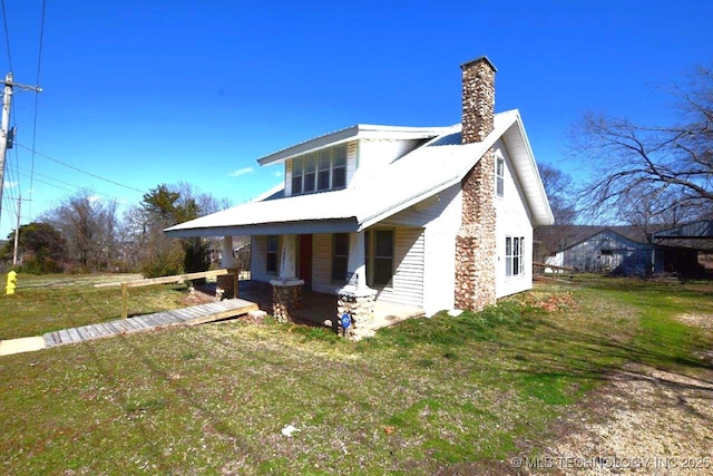 exterior space featuring a chimney, metal roof, and a yard