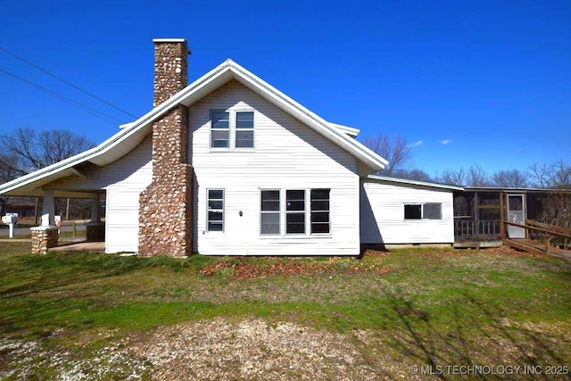 rear view of house featuring a lawn and a chimney