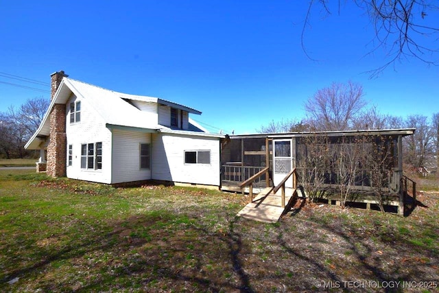 back of property with metal roof, a yard, and a sunroom