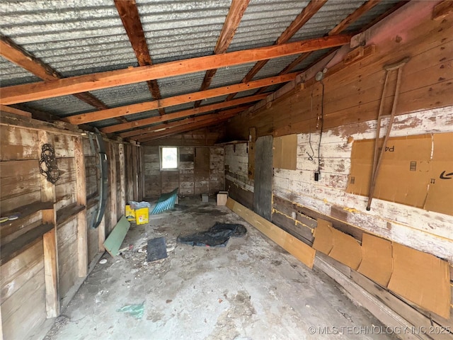 interior space featuring lofted ceiling, concrete floors, and wooden walls