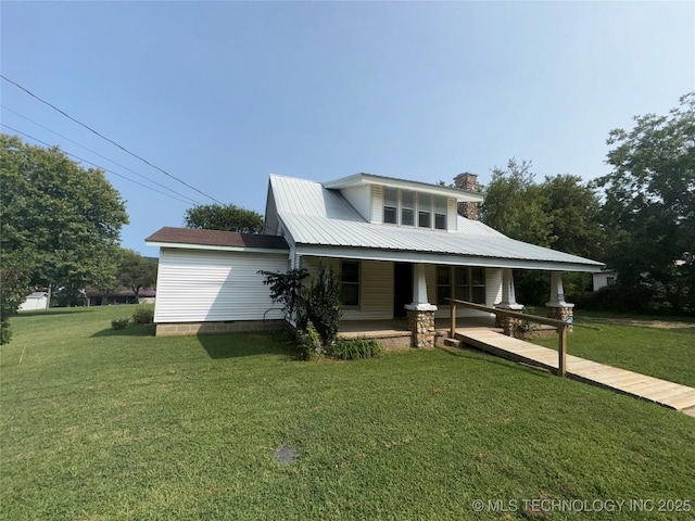 view of front of house featuring covered porch, a chimney, and a front yard