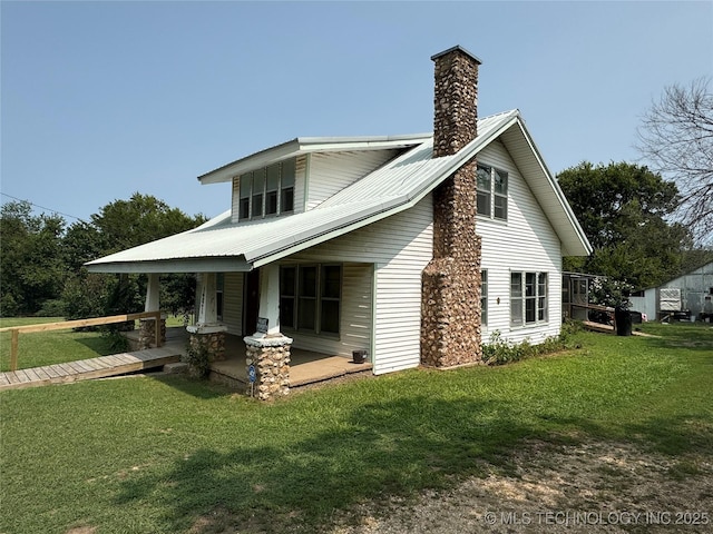 back of house featuring a chimney, metal roof, and a lawn