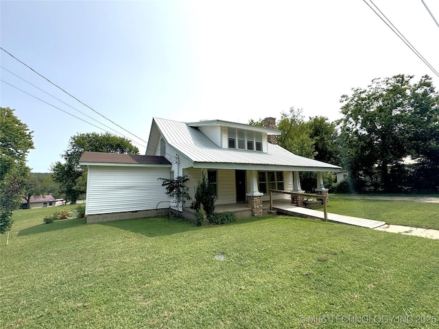 view of front of house featuring metal roof, a porch, a chimney, and a front lawn