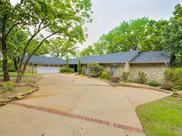 ranch-style house with stone siding, a shingled roof, driveway, and a garage