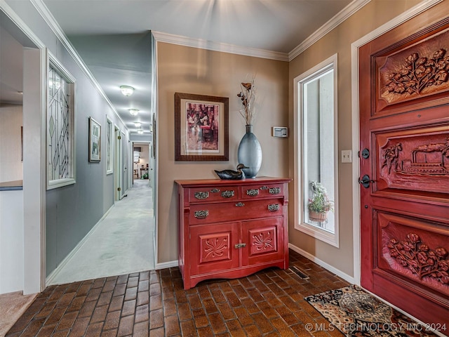 foyer entrance with baseboards, crown molding, and brick floor