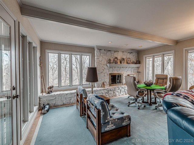 living room with ornamental molding, beam ceiling, a stone fireplace, and carpet