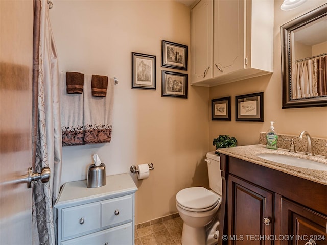 full bath featuring baseboards, vanity, and toilet