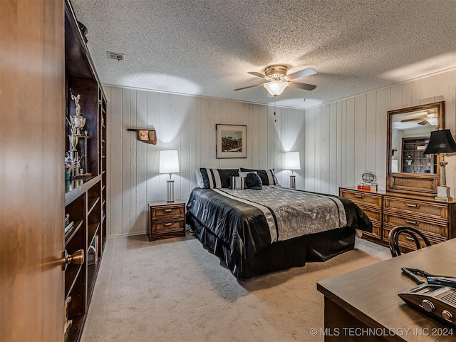 bedroom featuring a textured ceiling, ceiling fan, carpet floors, wood walls, and visible vents