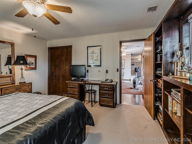 bedroom featuring wood walls, carpet, visible vents, and a textured ceiling
